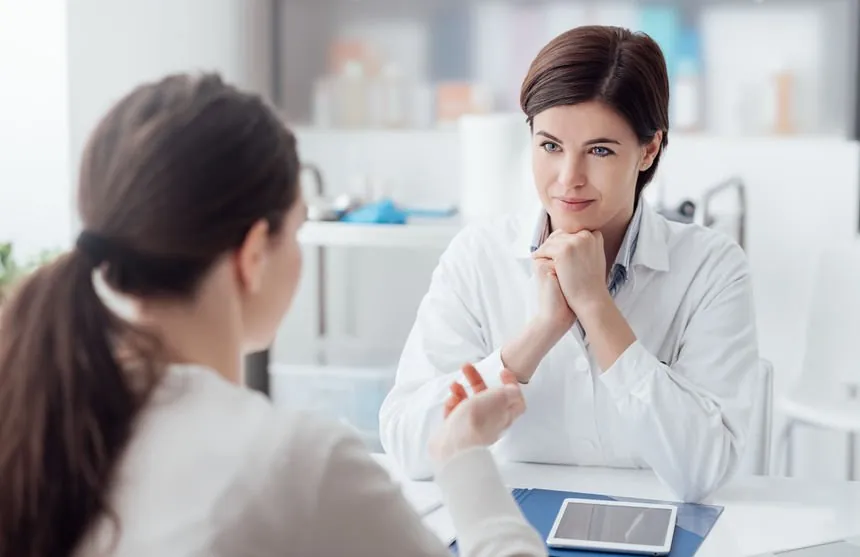 Doctor seated at an office desk, listening attentively to a patient during a consultation