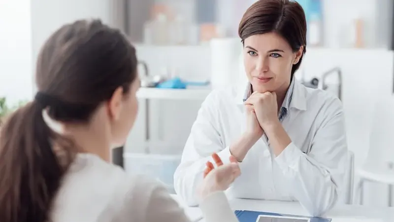 Doctor seated at an office desk, listening attentively to a patient during a consultation